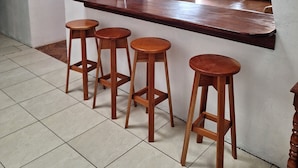 A kitchen with a wooden bar counter and four stools. - Bosque del Río Lodging (Monteverde)