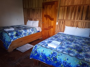 Two single beds with floral bedding, wooden headboards, and a wooden floor.