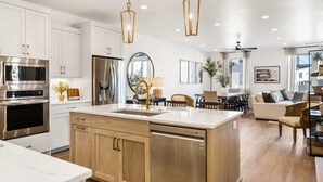 A modern kitchen with white cabinets, stainless steel appliances, and a wooden island. - Shoreline: Desert Color Lagoon + Beaches (St. George)