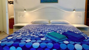 A bedroom with a bed, a painting on the wall, and a closet with hanging clothes. - Beautiful panoramic terrace overlooking the sea, with swimming pool (Finale Ligure)