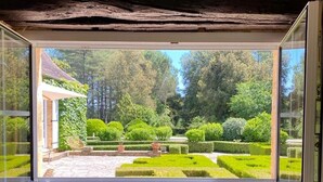 A room with a stone wall and a window overlooking a well-maintained garden with hedges and trees. - Manor of Quintefeuille /Tennis -exceptional estate for 12 people max (Journiac)