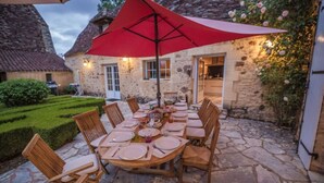 An outdoor dining area with a stone floor, wooden chairs, and a red umbrella. - Manor of Quintefeuille /Tennis -exceptional estate for 12 people max (Journiac)