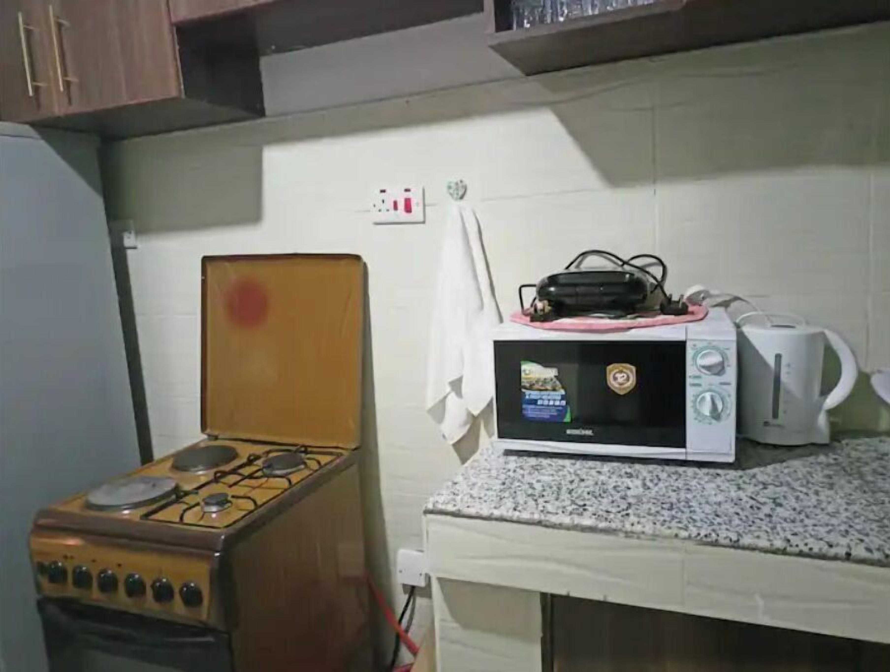 A kitchen with a gas stove, a microwave, and a kettle on the countertop.
