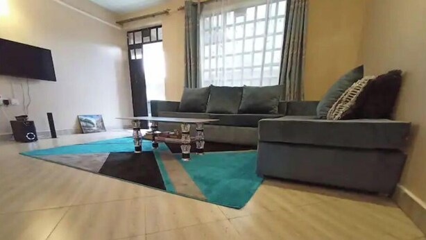 A living room with a sofa, a coffee table, and a rug. - A spacious & lovely 1 bedroom homestay in Nakuru (Nakuru)