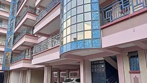 A multi-story residential building with balconies, a car parked in the driveway, and a staircase leading to the entrance. - A spacious & lovely 1 bedroom homestay in Nakuru (Nakuru)