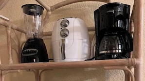 Une étagère de cuisine avec un mixeur, une machine à café et un four à micro-ondes.