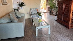 Un salon avec un canapé, un fauteuil, une table basse et des plantes en pot.