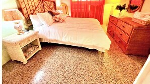 Une chambre à coucher comprenant un lit, une table de chevet, une commode, un miroir et une fenêtre avec des rideaux.