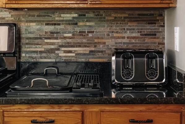 A kitchen with a black countertop, a stainless steel range, and a toaster.