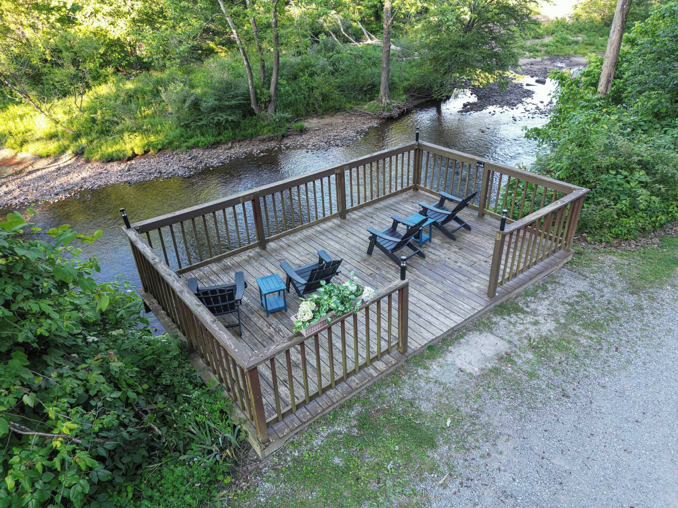 Une terrasse en bois avec des sièges extérieurs et une vue sur une rivière.