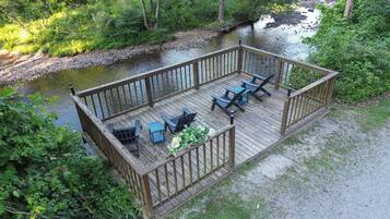 Une terrasse en bois avec des sièges extérieurs et une vue sur une rivière.