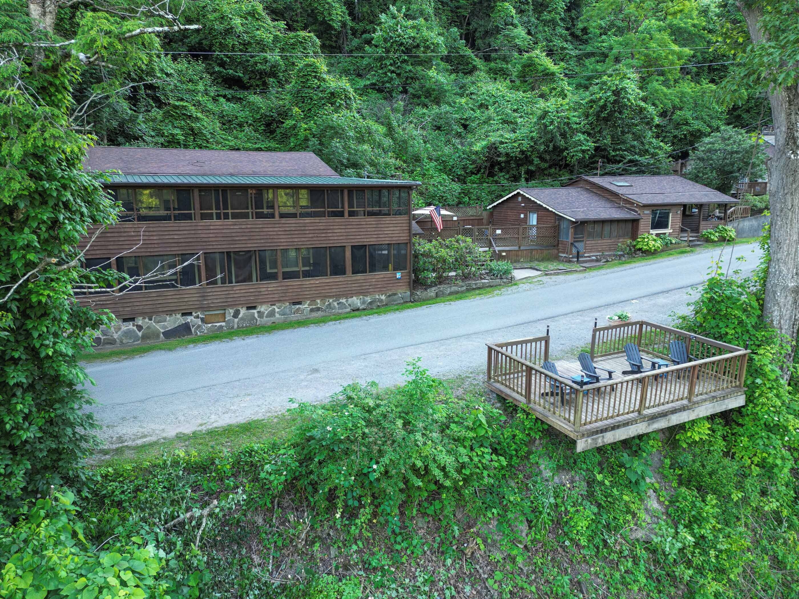 A cabin-style building with a stone foundation and a green roof, surrounded by dense forest.