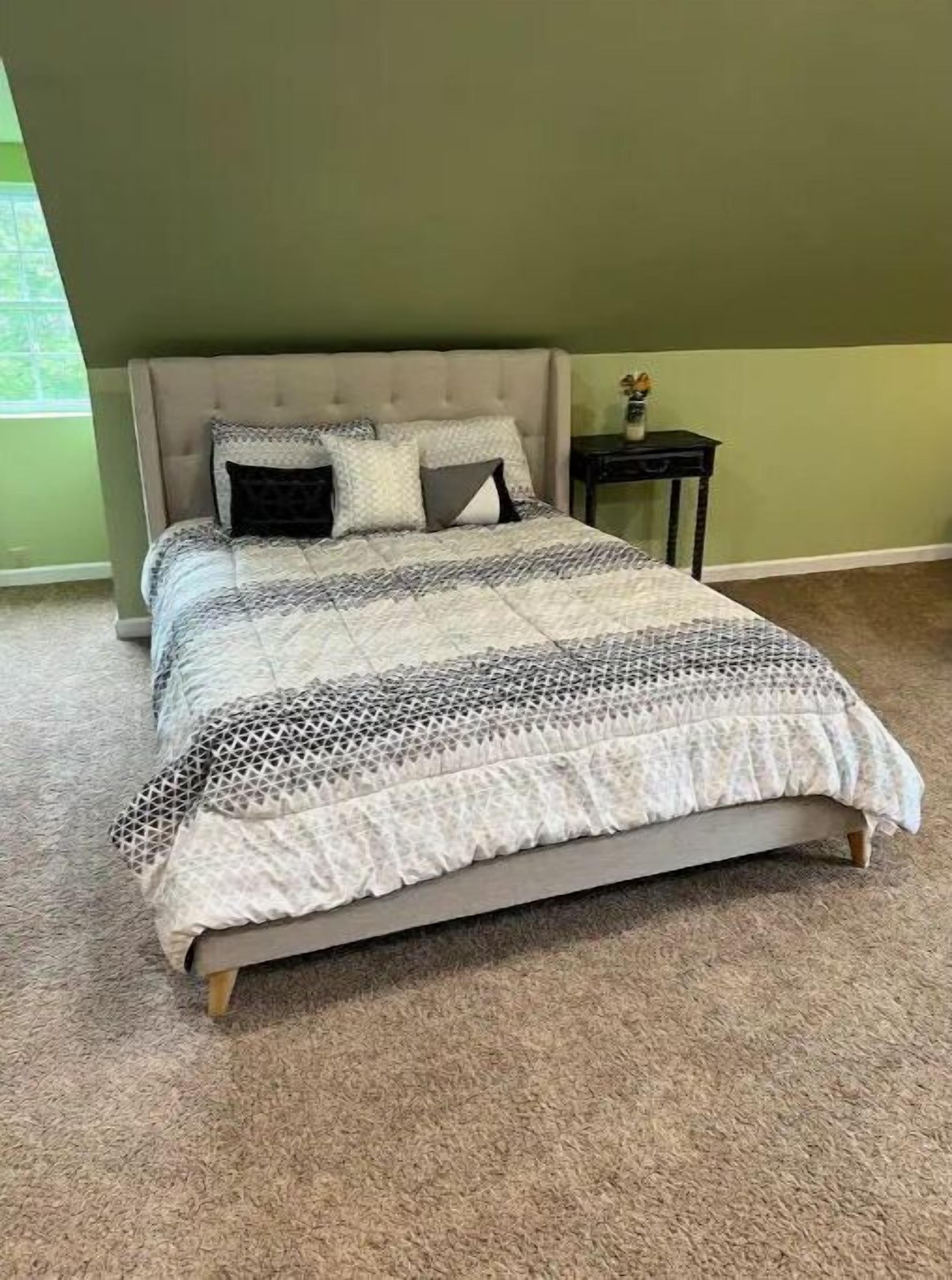 Un dormitorio con cama, mesita de noche y ventana.
