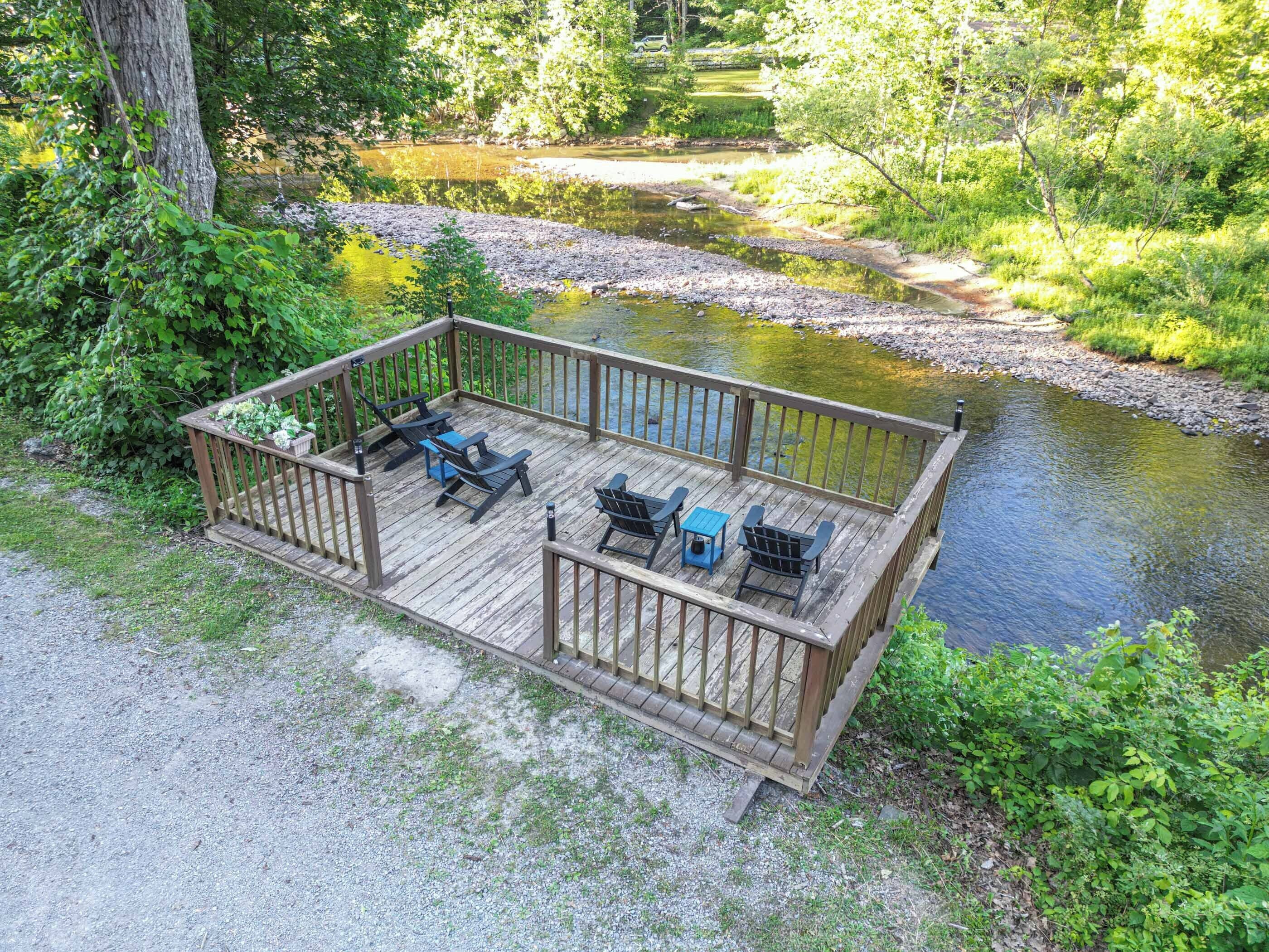 A wooden deck with outdoor seating and a view of a river.