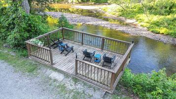 A wooden deck with outdoor seating and a view of a river.