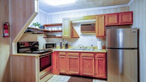 A compact kitchen with wooden cabinets, a stainless steel refrigerator, a microwave, an oven, and a coffee maker. - Secluded Lodge*Full kitchen + King Bed (Elkins)