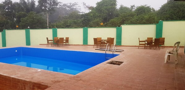 Relax by the clear pool surrounded by a deck and lush greenery.