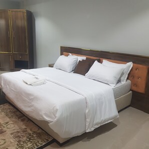 Relax in a spacious room with a large bed, a wardrobe, and a rug.