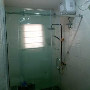 Bathroom features a glass-enclosed shower with handheld showerhead and wall-mounted faucet.