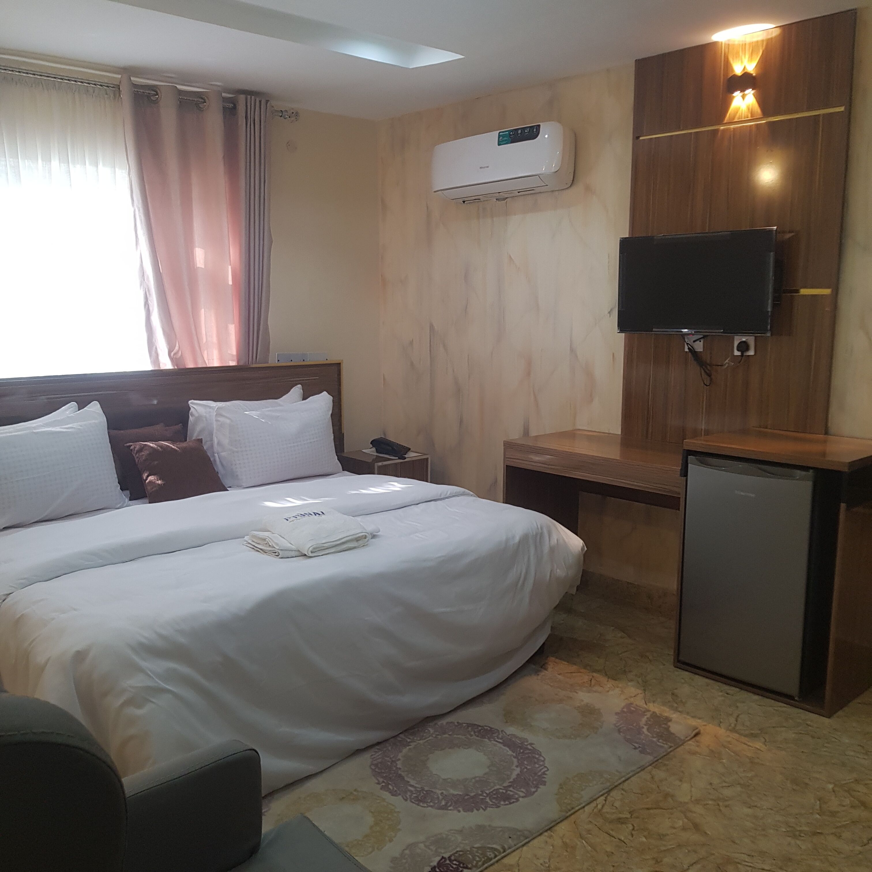 Een hotelkamer met een groot bed, een bureau, een televisie en een koelkast.