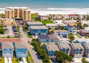 Un hotel costero con edificios de varios pisos, un estacionamiento y vista a la playa.
