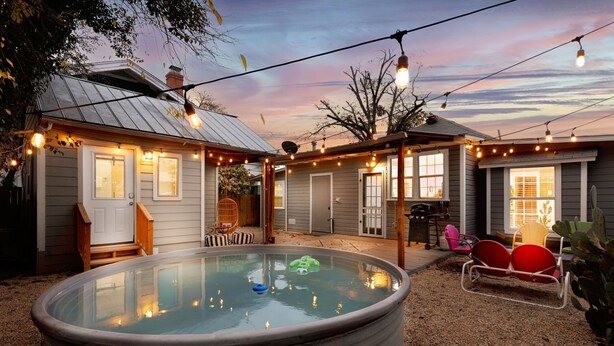 Un jardin avec un jacuzzi, des guirlandes lumineuses et un coin salon extérieur.