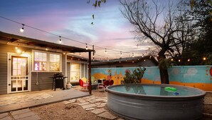 Un jardin avec une piscine, des meubles de patio et des guirlandes lumineuses.