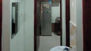 Ein schmaler Flur mit einer Küche, ausgestattet mit einem Kühlschrank und einem Spülbecken.