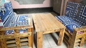 Ein Holztisch und zwei gestreifte Sofas in einem Raum mit einer rosa Wand und einer Wand mit Grau-Struktur.