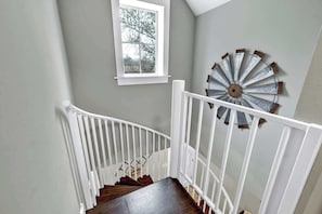Eine Treppe mit weißen Geländern und Holzboden, die zu einem Raum mit Fenster und einer dekorativen Metallwandverkleidung führt.