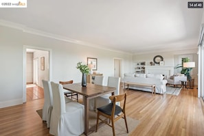 Ein geräumiges Wohnzimmer mit Essbereich, weißen Möbeln und einem Kamin.