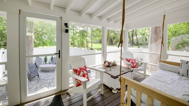 A covered porch with white furniture, a swing, and a view of the outdoors. - Bloomington Bungalow - Steps to Campus! (Bloomington)