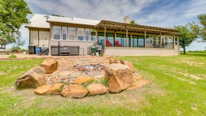 A two-story house with a covered patio area and a stone fire pit in the front yard. - Modern Lakehouse w/ Stunning Views & Hot Tub! (Granger)