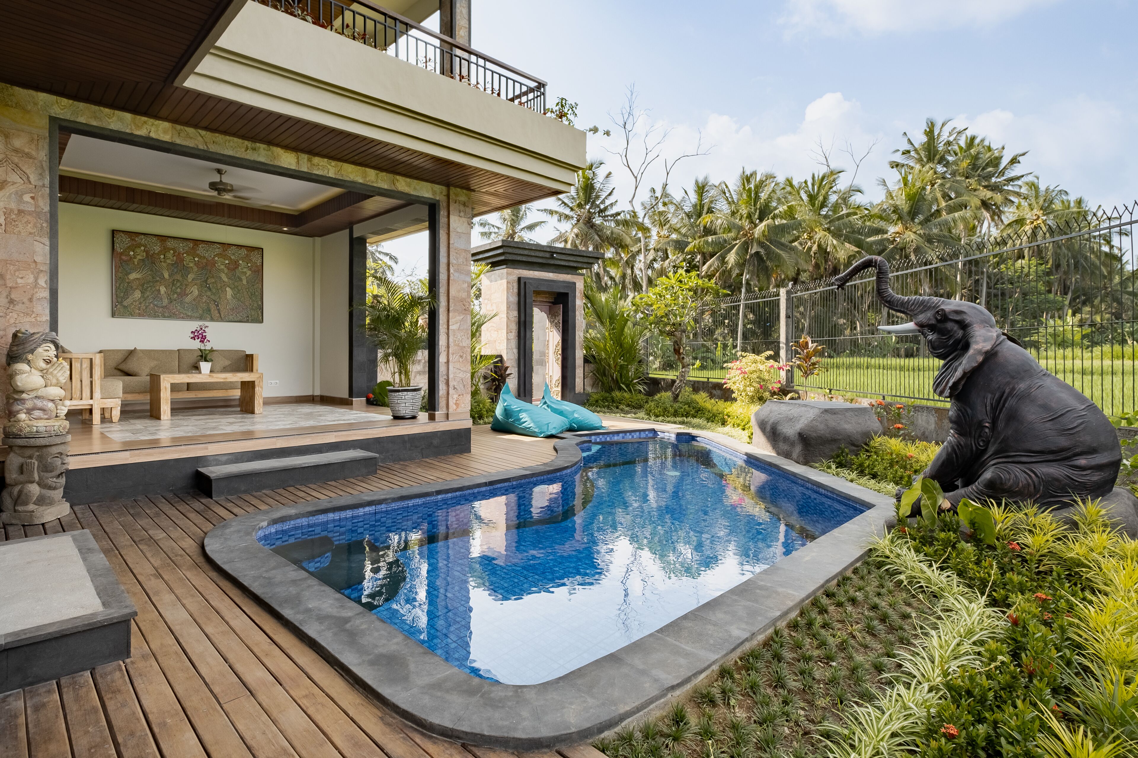 A modern house with a swimming pool, a balcony, and a statue of an elephant.