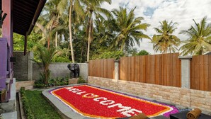 Un jardín tropical con felpudo, palmeras y mobiliario exterior.
