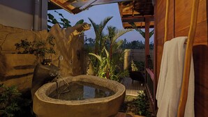 Una fuente de piedra con estructura de madera y una toalla colgada a la derecha.