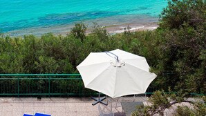 Un espace aménagé sur la plage, avec un parasol blanc, des chaises longues bleues et une table.
