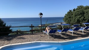 Une piscine avec des chaises longues et vue sur la mer.