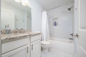 Ein modernes Badezimmer mit einem мраморным Waschbecken, einer Toilette und einer Badewanne.
