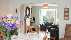 Een woonkamer met een eettafel, stoelen, een bank en een open haard.