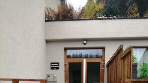 A set of outdoor steps leading to a wooden door with glass panels, a sign indicating the address, and a security camera above the door. - Studio in the heart of nature, 800 m from La bresse-hohneck ski resort (La Bresse)