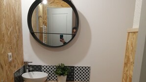 A bathroom with a wooden vanity, a round mirror, a white sink, a potted plant, and a toilet. - Studio in the heart of nature, 800 m from La bresse-hohneck ski resort (La Bresse)