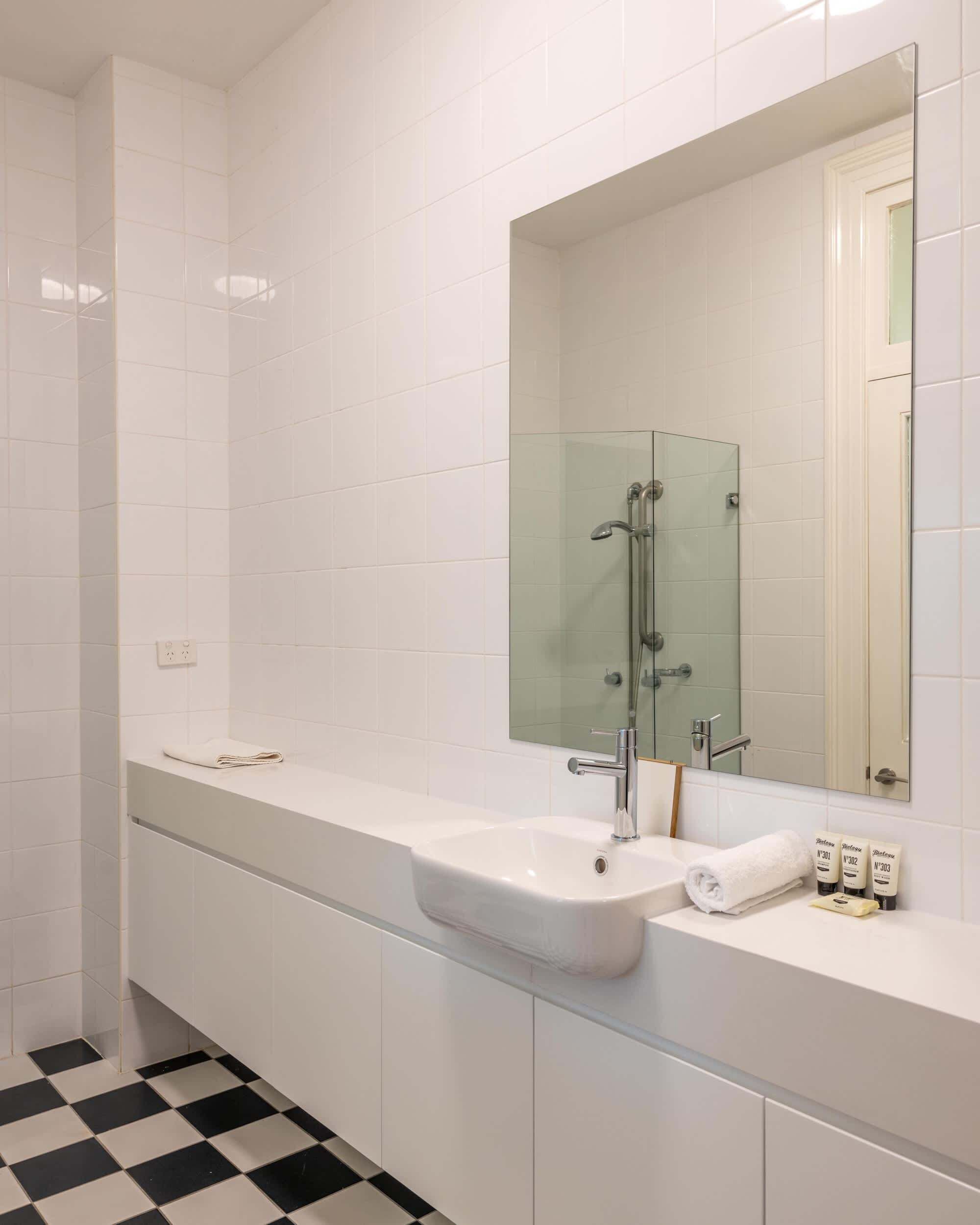 Een moderne badkamer met een ruime wastafel, een glazen douchecabine en een spiegel boven de wastafel.