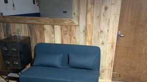 Et værelse med en blå sofa, trægulv, et metalkabinet og en trævæg.
