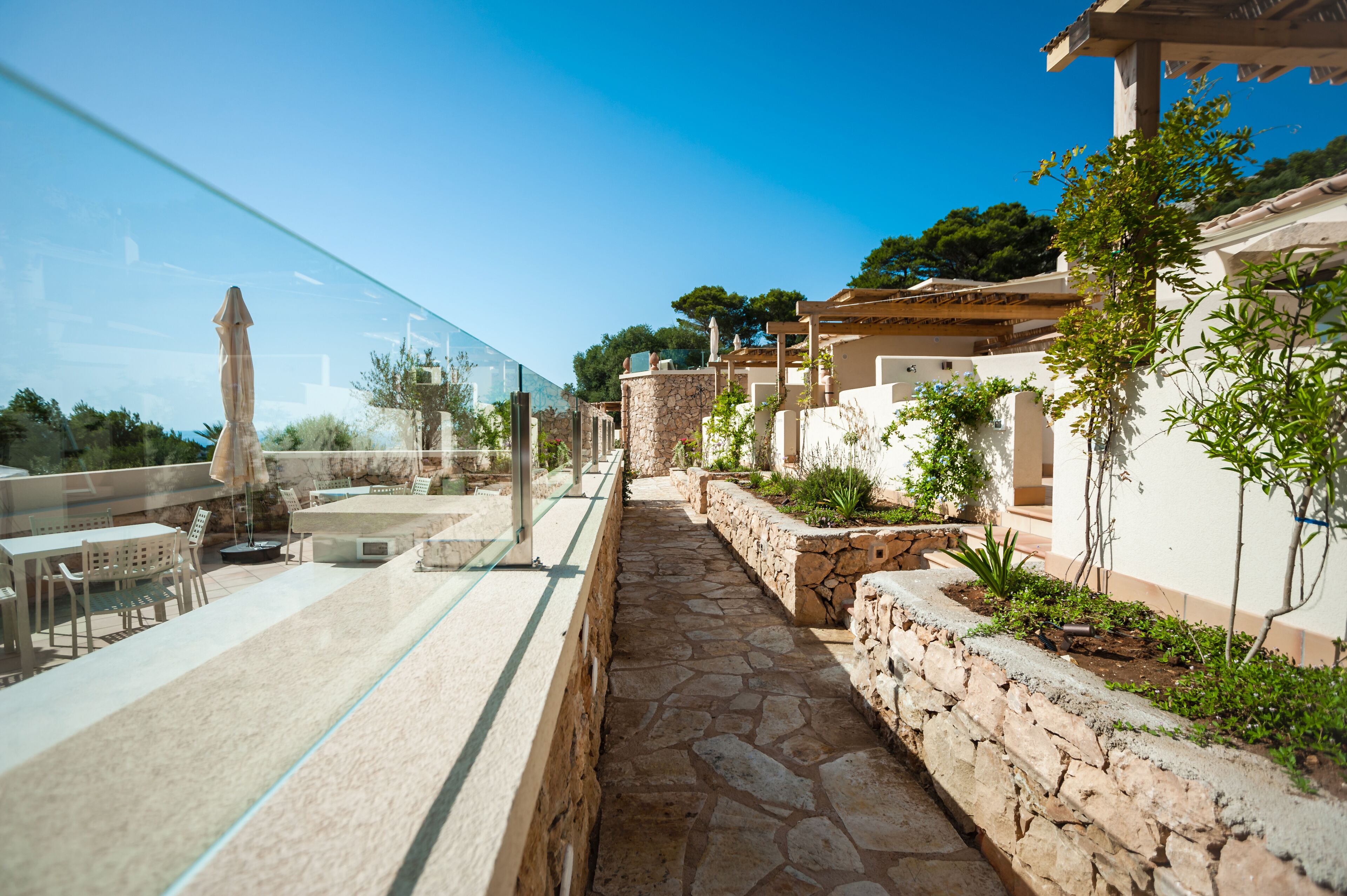 Une terrasse sur le toit avec un revêtement de sol en pierre, du mobilier d’extérieur et une balustrade en verre.