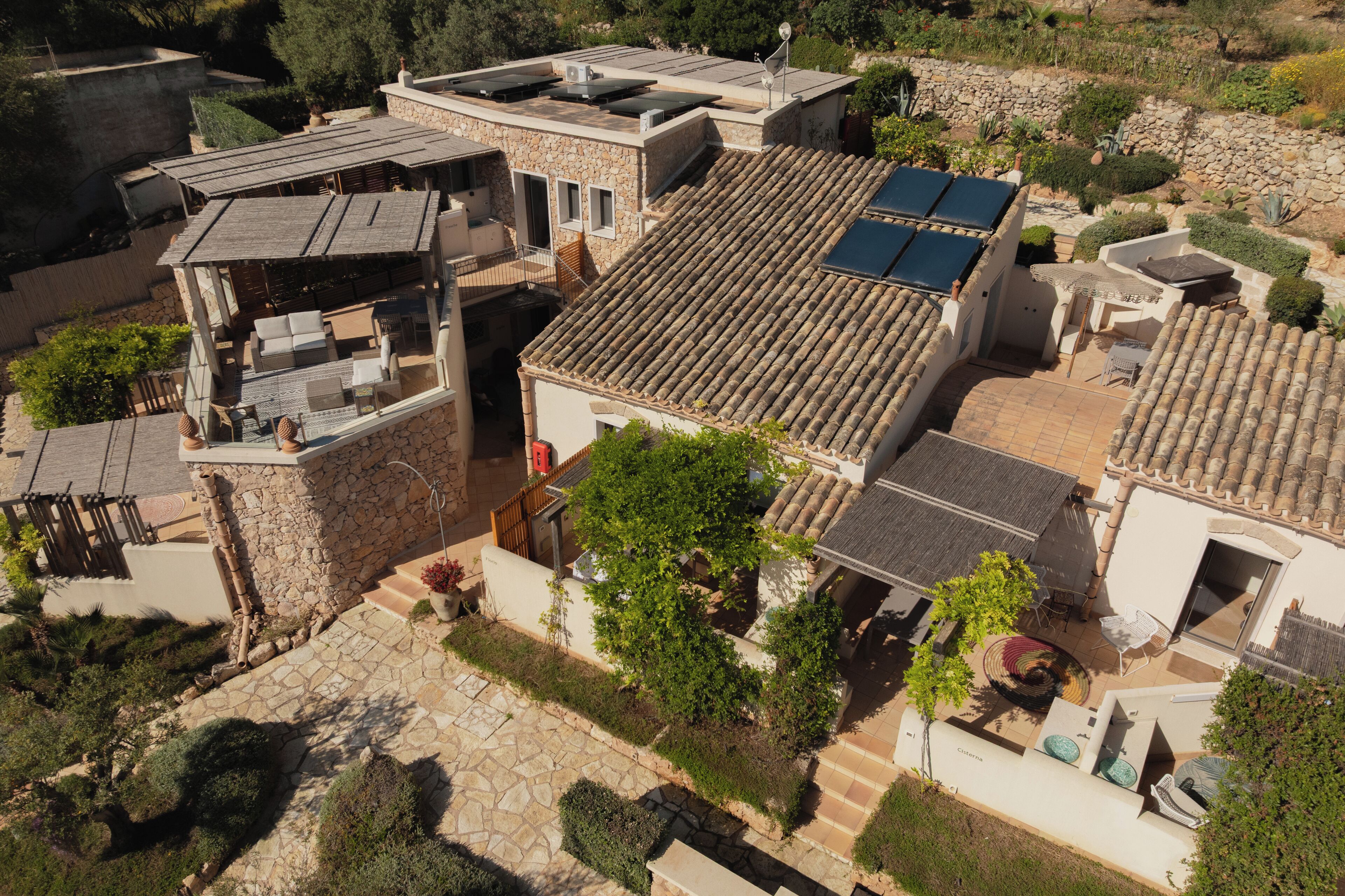 Un immobile residenziale con tetto in tegole, pareti in pietra e patio arredato.