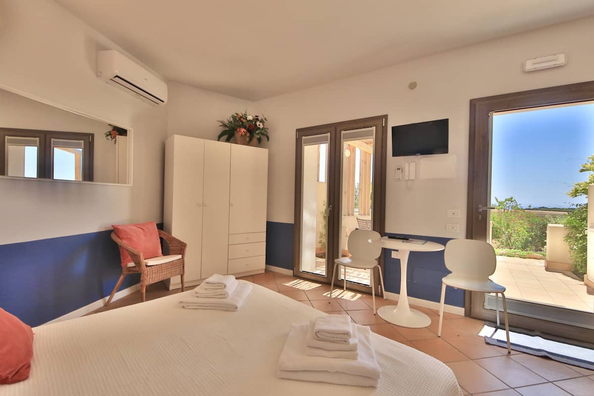 Ein Hotelzimmer mit einem Bett, zwei Stühlen, einem Kleiderschrank und einem Fernseher.