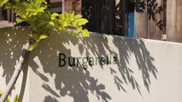 Una pared con el nombre "Burgarella" y sombras de hojas y ramas.