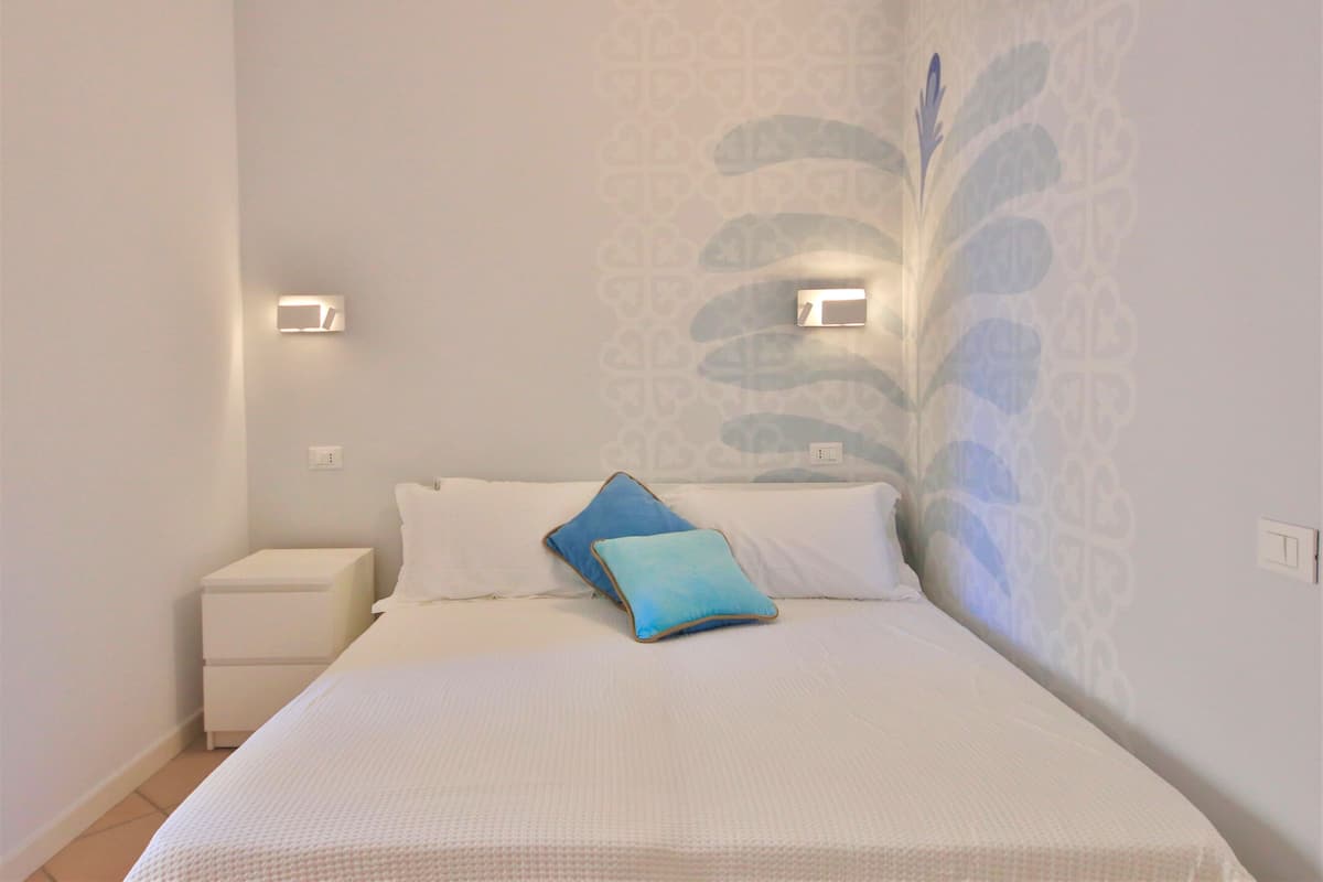 Ein Schlafzimmer mit Bett, Nachttisch und Wandleuchten.