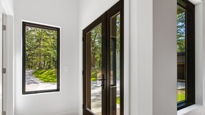 A room with a large window and a sliding glass door leading to an outdoor area. - Serene Retreat Awaits: Welcome to Endless Views,Your Luxurious Contemporary Home (Muskegon)